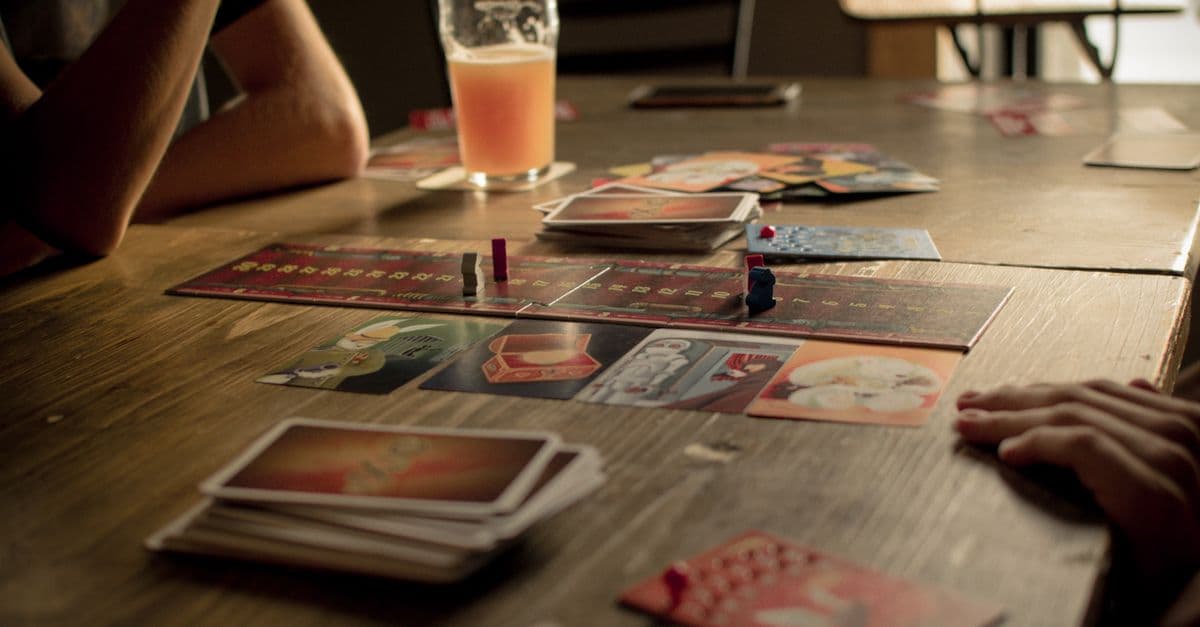Residents and a caregiver laughing together over a board game at the kitchen table.