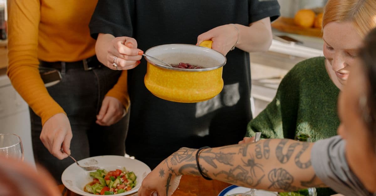 Friends preparing a home-cooked meal together in a sunlit kitchen.
