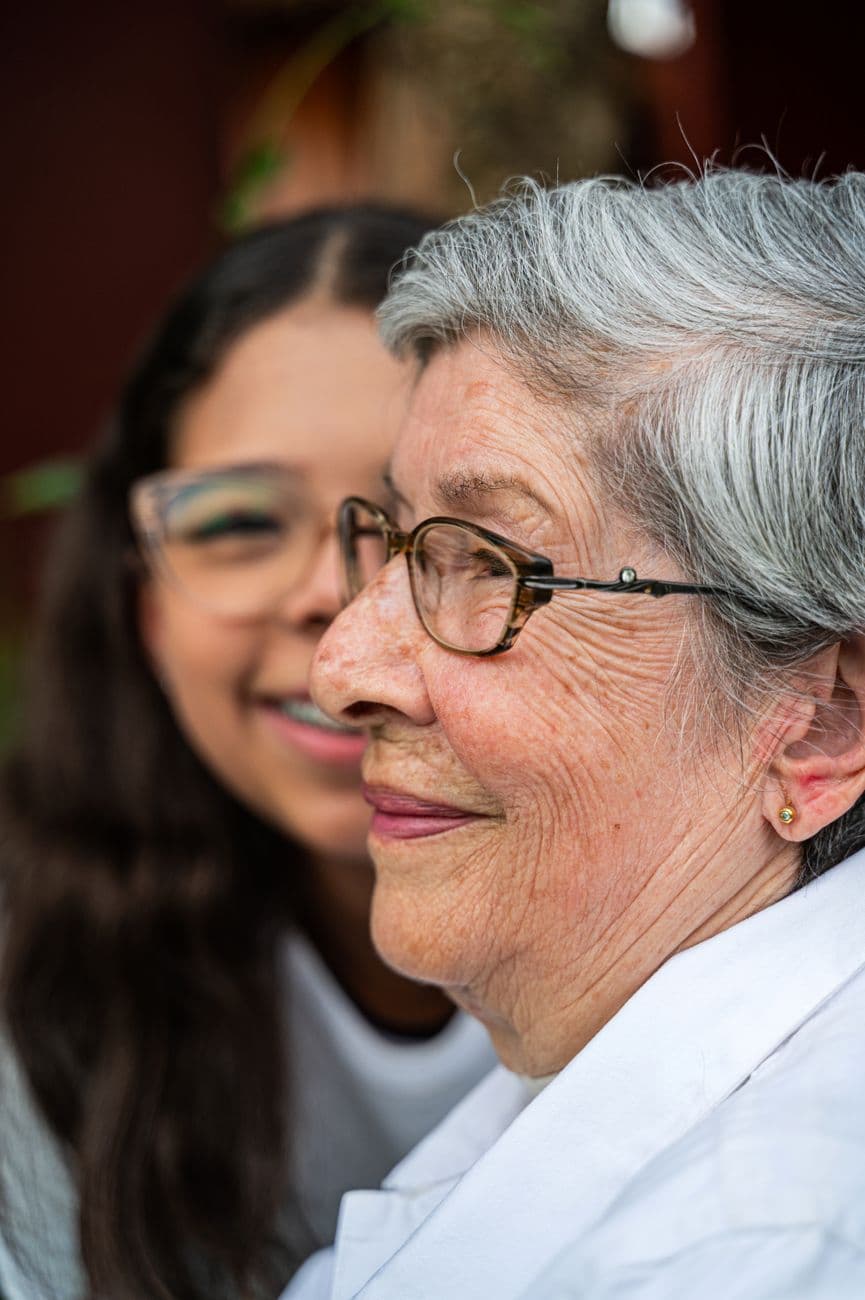 A caregiver and a resident smiling warmly together.
