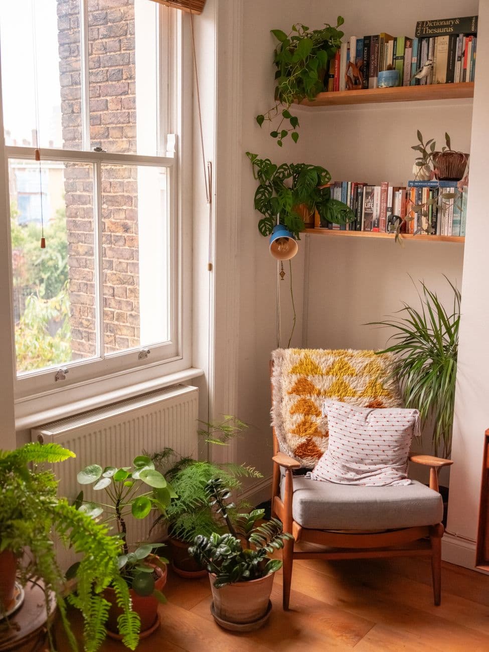 A quiet reading nook beside a sunny window and houseplants.